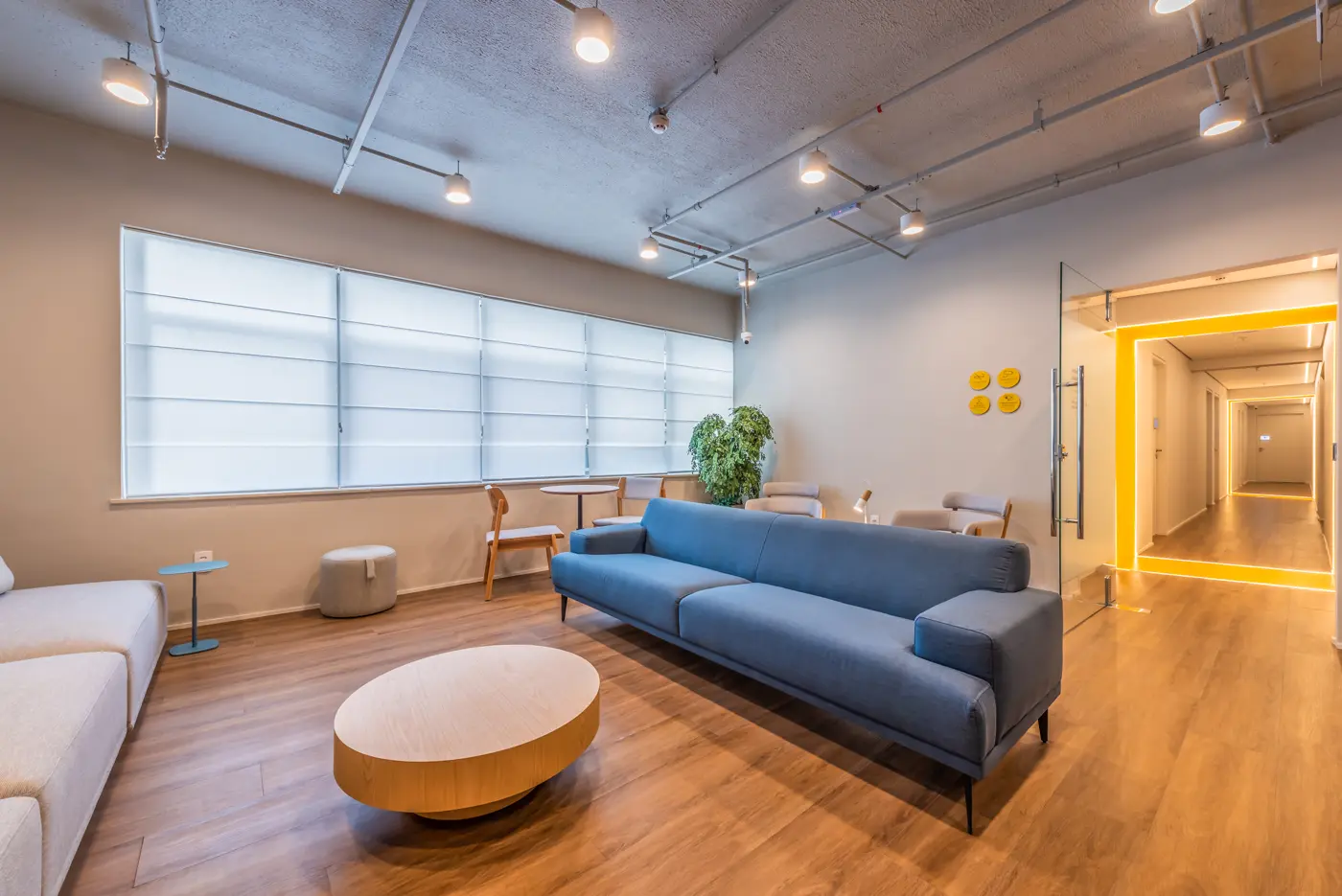 Sala de espera em Botafogo, com sofá azul e mesa de centro redonda de madeira