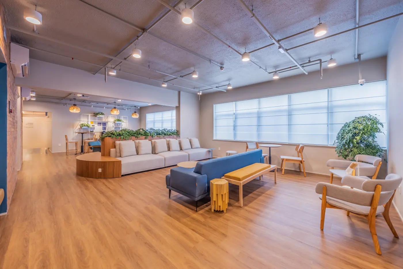 Lounge amplo em Botafogo, com sofás claros, plantas e janelas amplas